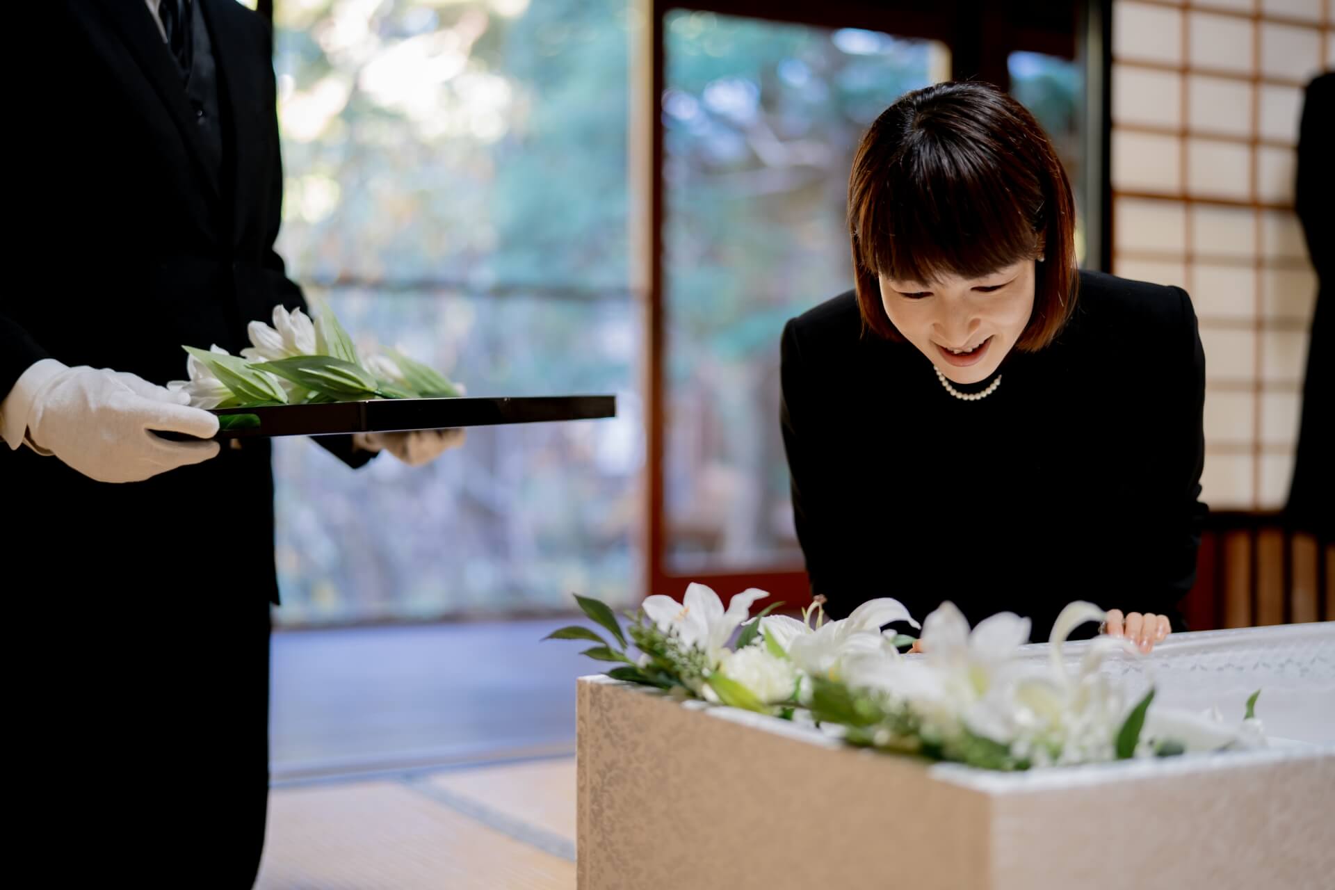 白い花を見つめる喪服の女性